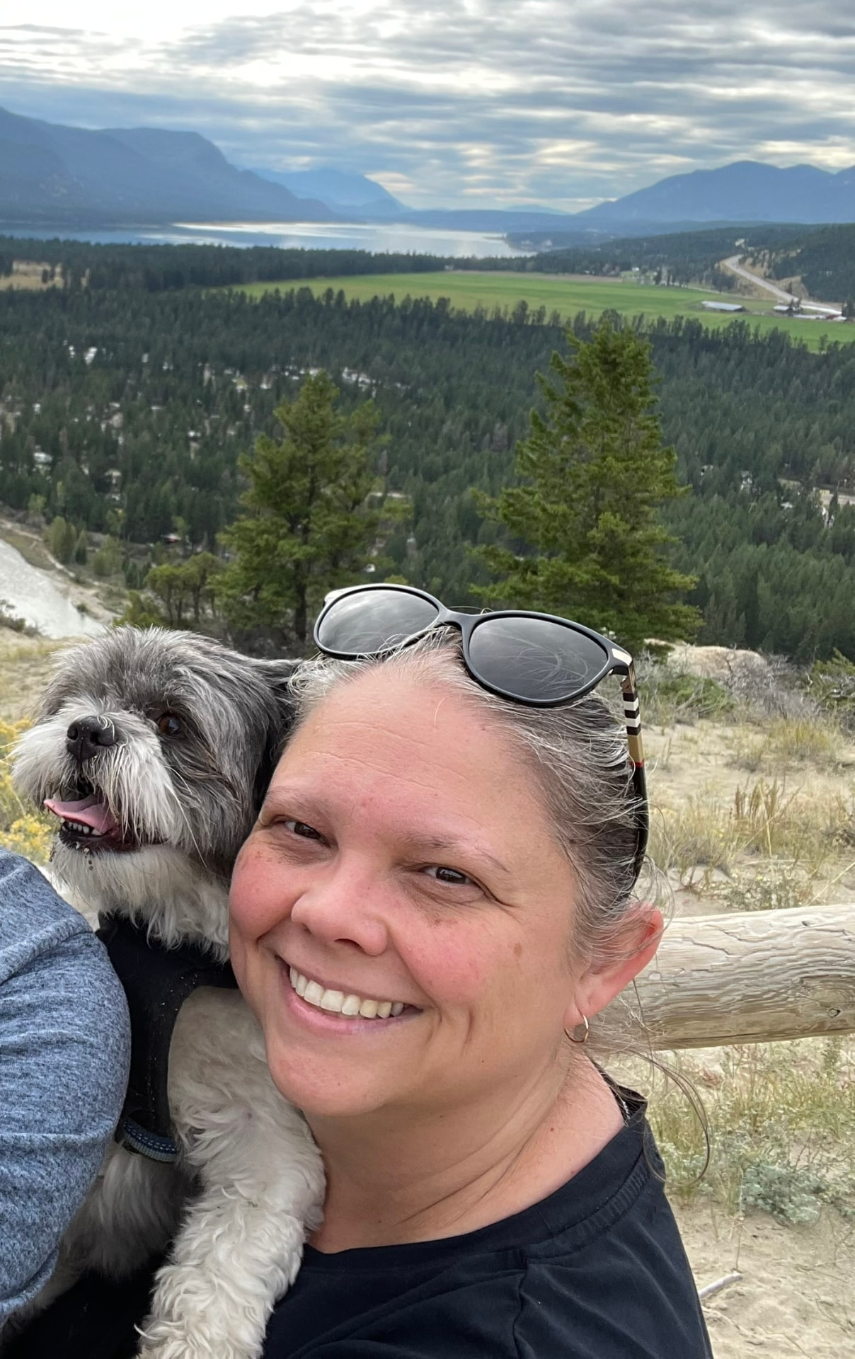 Joy, owner of Paws Poop and Play, outdoors with a happy dog